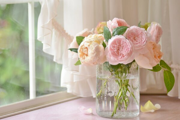 Roses de couleur rose tendre dans un vase en verre