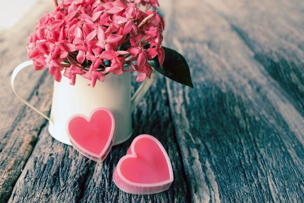 Cuori rosa vicino a una tazza bianca con fiori rosa