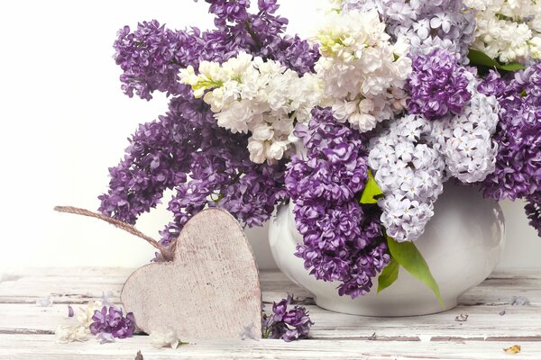 May lilac in a vase and a wooden heart