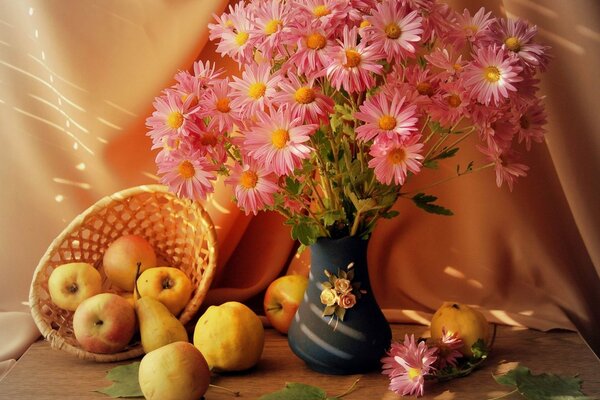 Fleurs debout dans un vase et à côté d un panier de pommes