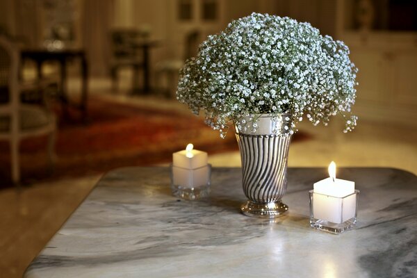 Sur la table une bougie et un vase avec un bouquet d air