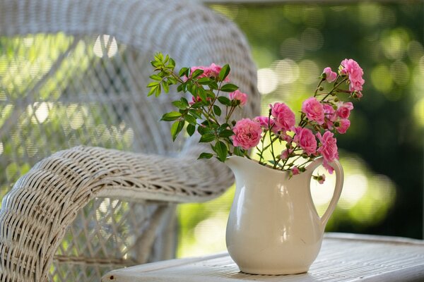 Fleurs roses dans une cruche sur une table près d une chaise