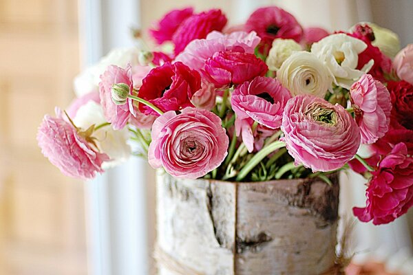 Delicate flowers of peonies and ranunculus in a birch bark basket