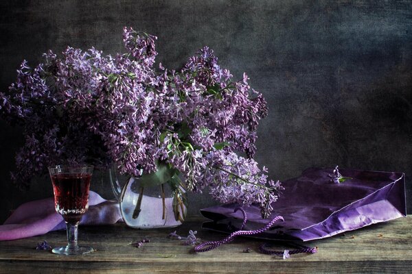 Bouquet di lillà in un vaso con un bicchiere di vino