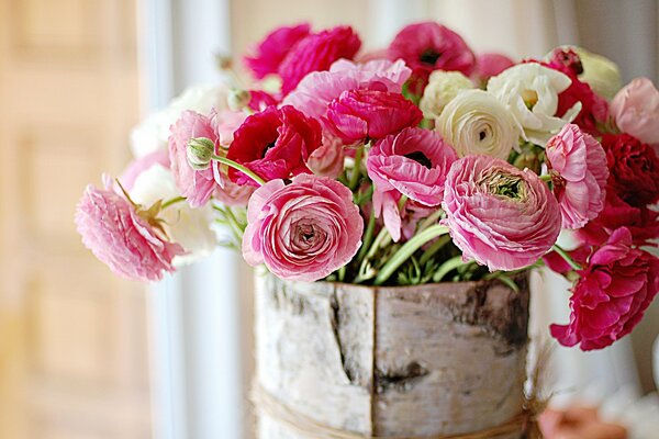 El más delicado ramo rosa brillante de la belleza asombrosa de las flores en la cesta de la corteza de abedul sobre el fondo claro marrón