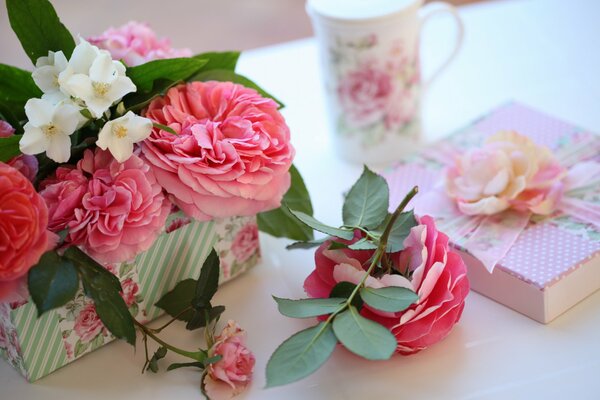 Caja de regalo, taza y rosas en la mesa