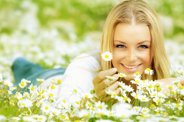 Blonde Mädchen auf dem Feld mit Gänseblümchen lächelnd