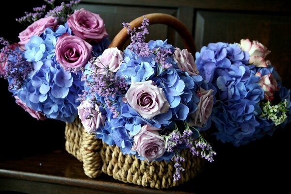 Trois bouquets bleus de roses dans un panier