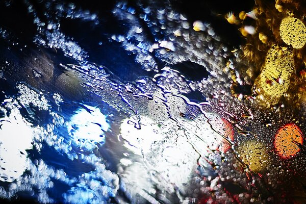 Luces de la ciudad nocturna en el cristal mojado