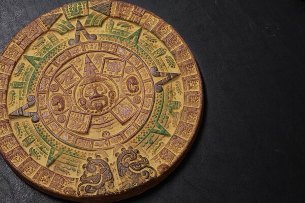 Calendario azteco o simboli insoliti su un emblema circolare su sfondo nero