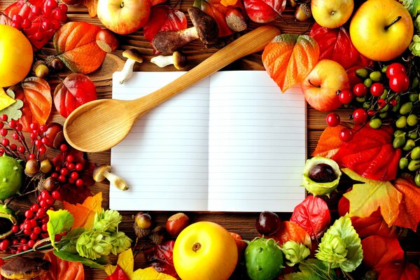 A notebook and a wooden spoon on the table with the gifts of autumn