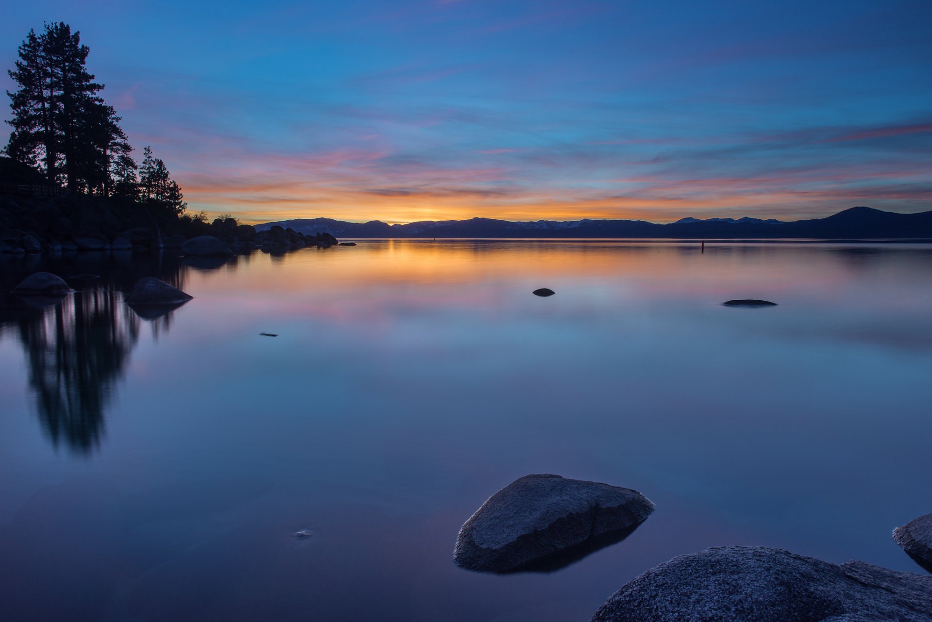 stati uniti d america lago acqua superficie liscia riflessione riva rocce alberi sera arancione tramonto blu cielo