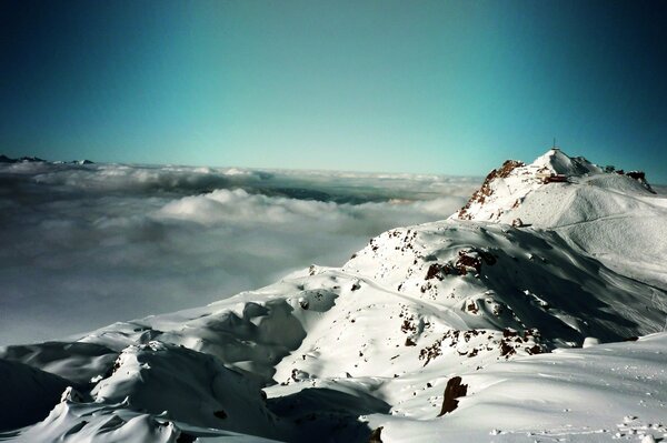 Una cresta Nevada de montañas altas por encima de las nubes