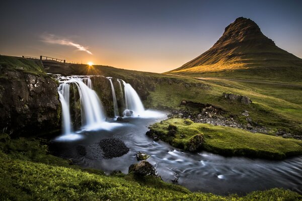 Ein Wasserfall mit einem Fluss auf dem Hintergrund eines einsamen Berges