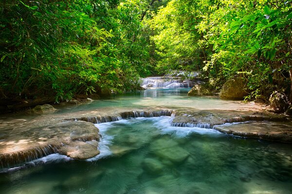 Fiume in Thailandia tra fogliame con una piccola cascata