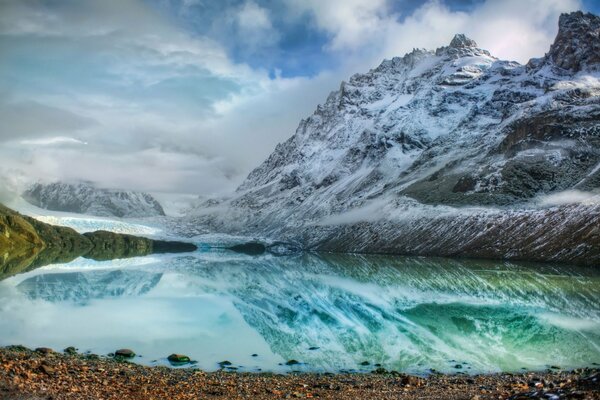 Transparent mountain lake, snow-covered rocks