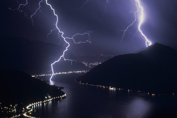 Blitze über Fluss und Hügel in der Nacht