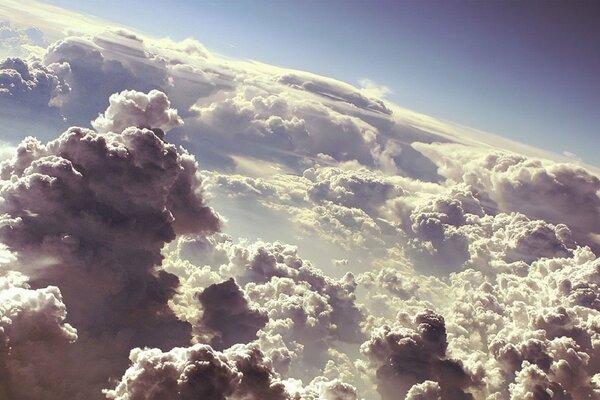 Clouds above the ground, illuminated by the sun, the view from the plane