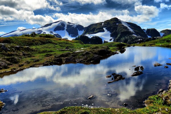 Die Wolken spiegeln sich im See am Fuße der Berge wider