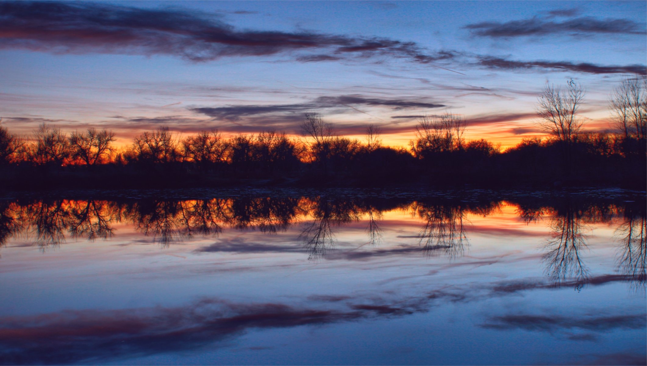 night twilight orange sunset blue sky clouds tree river water surface of silence reflection