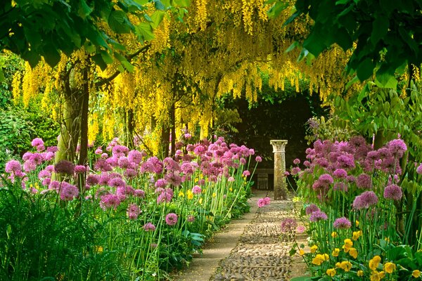 Eine Allee aus Blumen und gelben Bäumen, die zur Säule führt