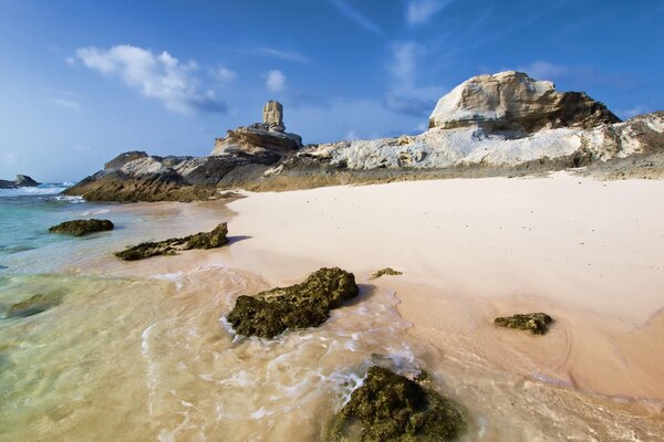 Stone beach near the sea. Clear sky against the background of rocks. Rocky stone shore. The purest water