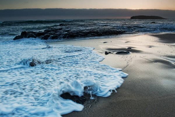 Foamy sea waves wash the sand