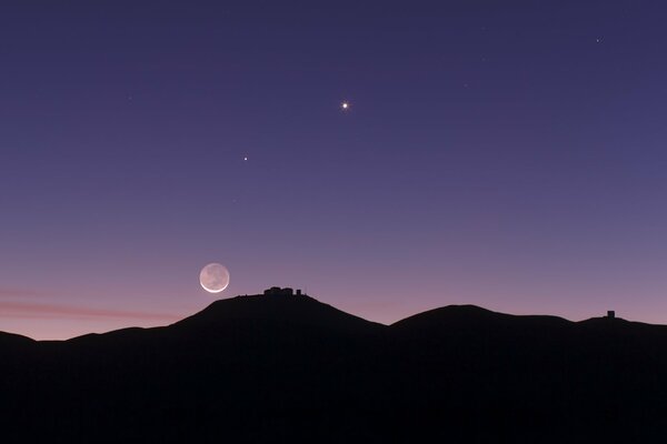 The starry sky. Dark image of mountains. A planet in the sky