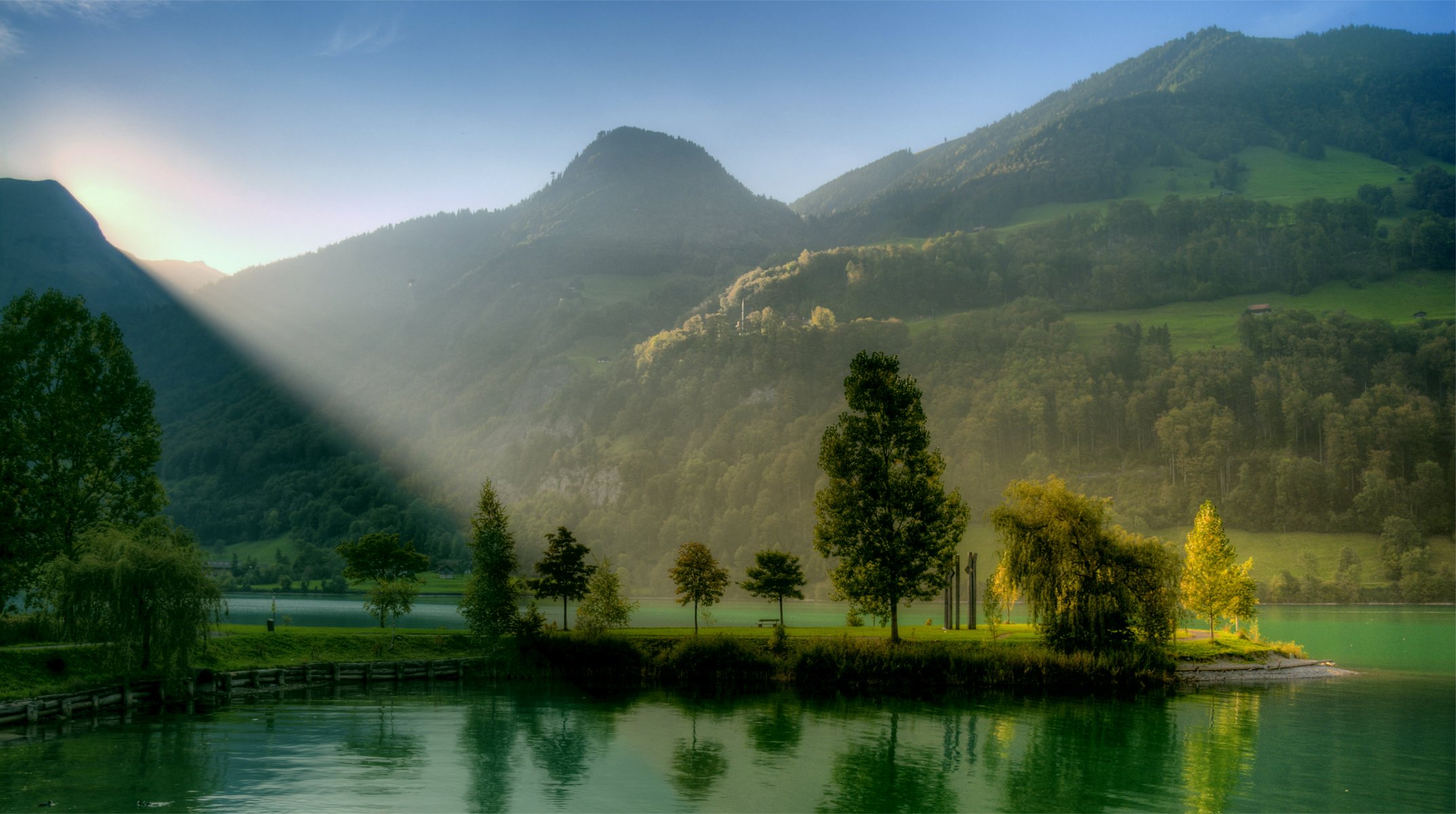 montagnes collines arbres verdure rivière bleu sans nuages ciel soleil lever du soleil lumière rayons paysage