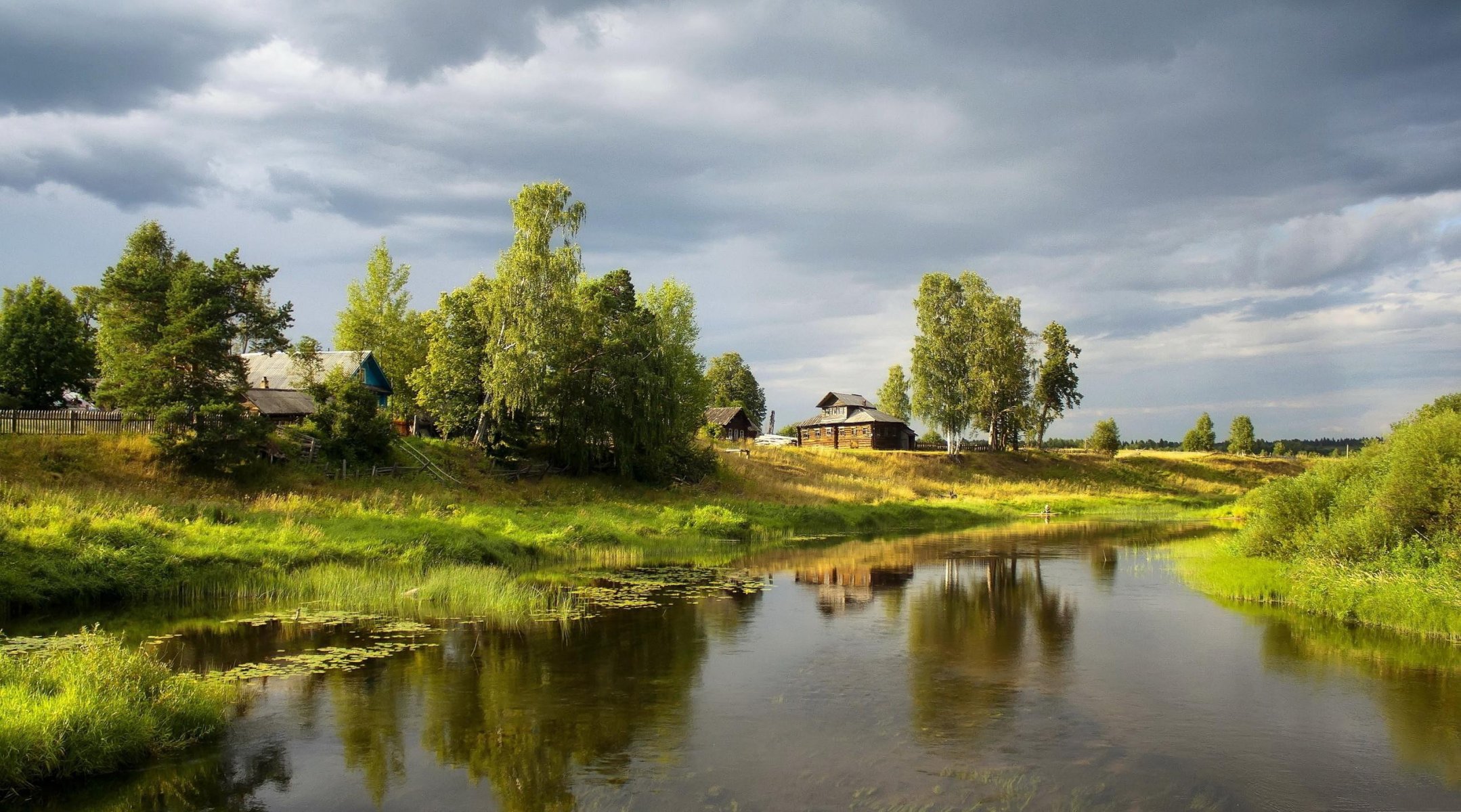 village houses village trees shore grass pond gray sky