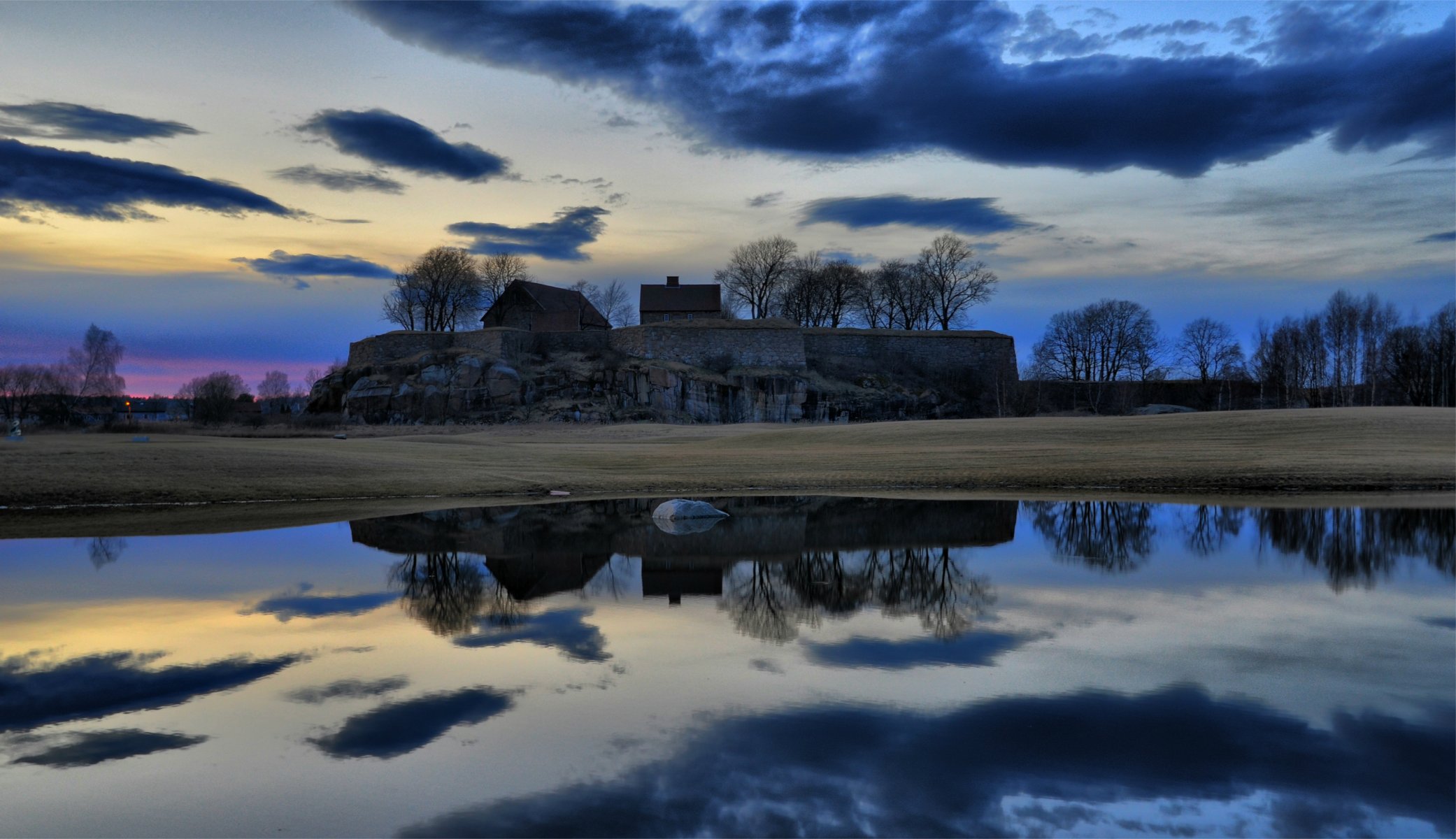 tarde puesta del sol cielo nubes casas árboles claros estacas apuestas agua superficie reflexión