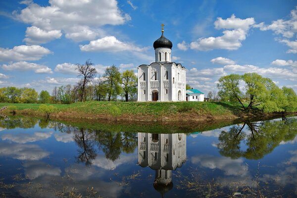 Белая церквушка с синим куполом на берегу голубого озера