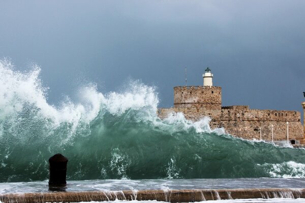 A powerful wave on the background of a lighthouse