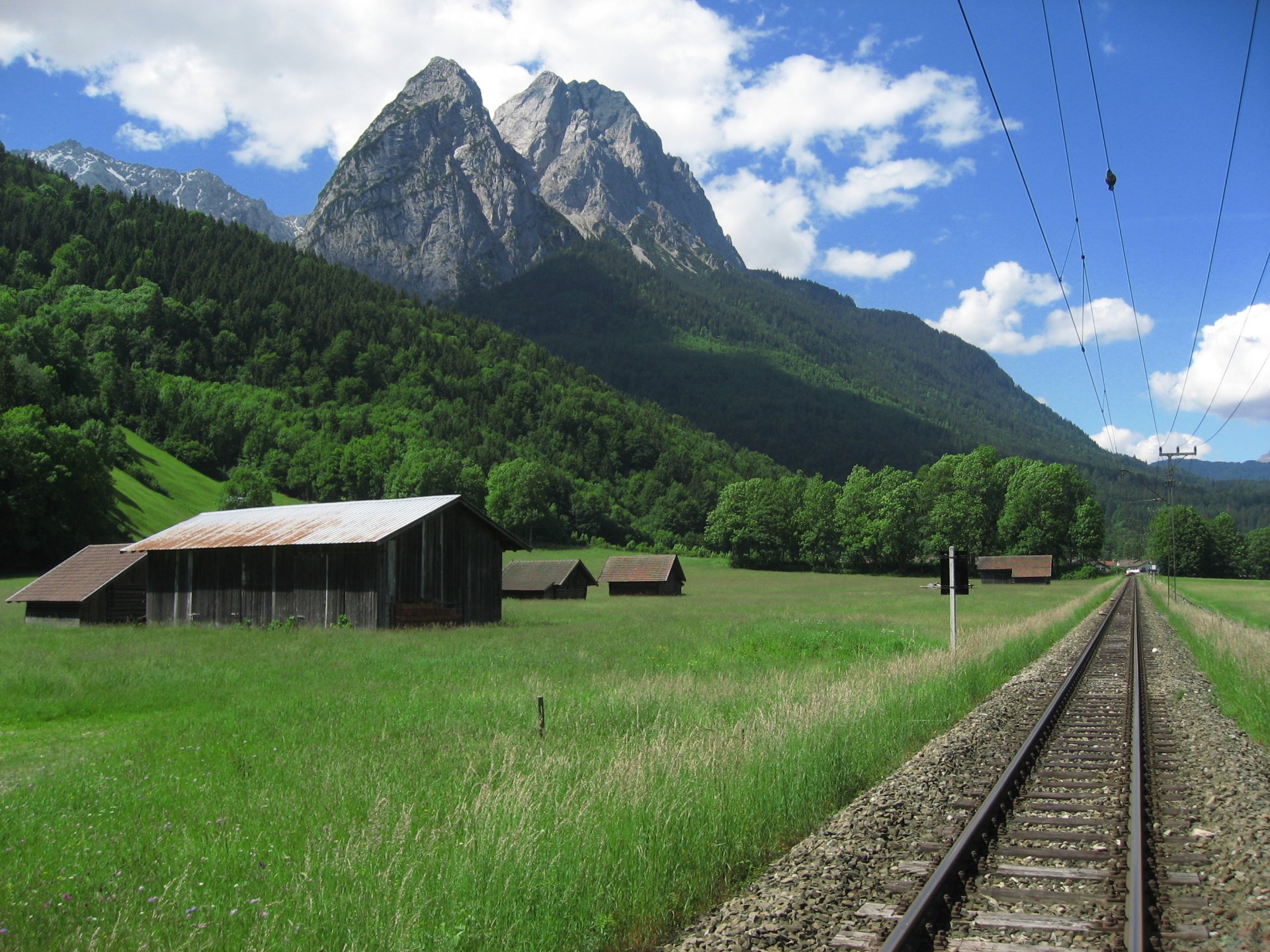 railway road rails wires mountains valley sky clouds nature photo peak peak mountain landscape houses clearing grass forest tree