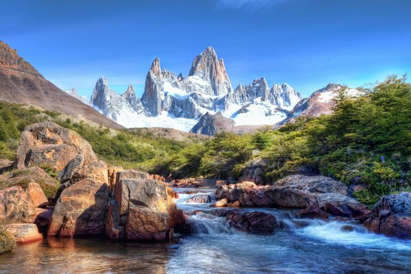 Montagne innevate con cascata e pietre