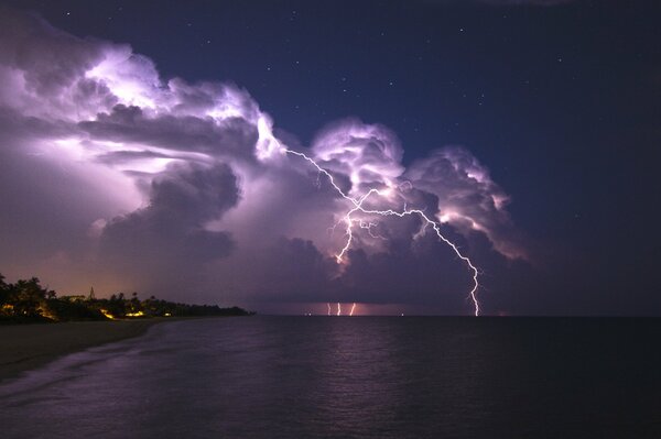 Flashes of lightning and a thunderclap in the black and purple night sky