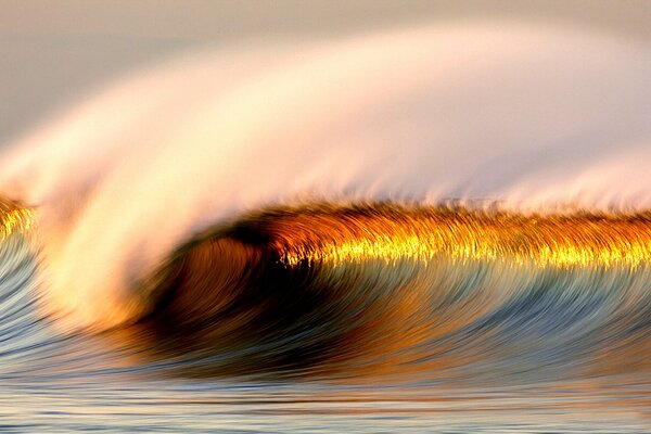 The rainbow crest of an ocean wave in a spray of foam