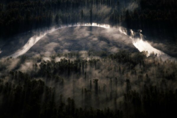 Fog spreads over the river and the dense forest