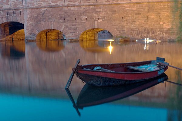 Boot auf der abendlichen Wasseroberfläche des Kanals in der Nähe der Brücke in Straßburg