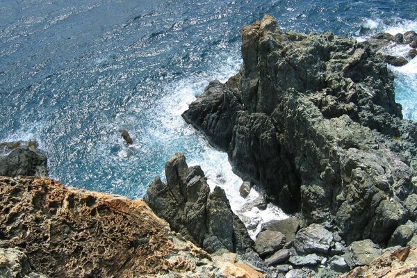 The sea with blue-green waters washes steep cliffs