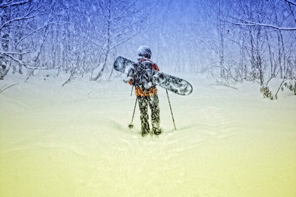 Hombre en el bosque de invierno en una tabla de snowboard