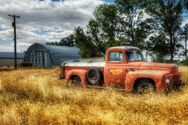 Camion orange près du hangar dans le champ