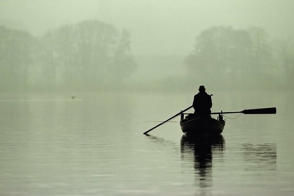 A lonely fisherman on a boat in the fog