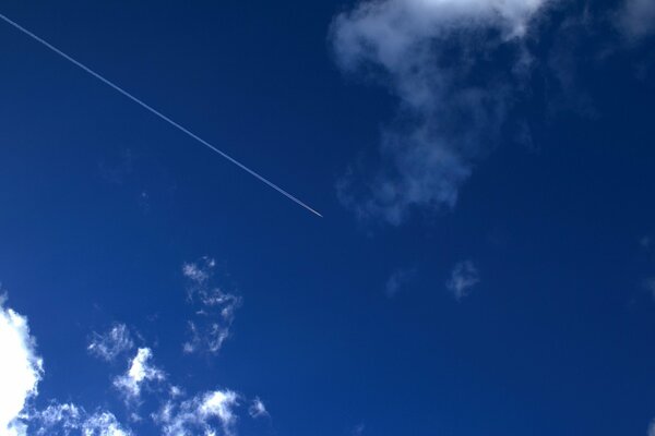 Rastro de un avión en el cielo azul entre las nubes