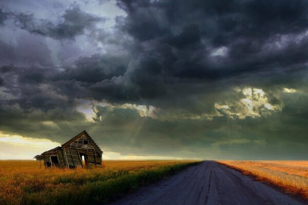 El camino bajo el cielo tormentoso y el granero en el lado