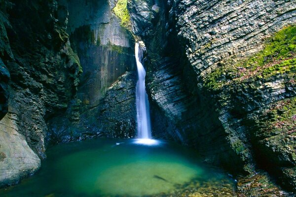 A shining waterfall flows down from the stones