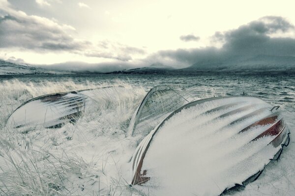 Boote am Flussufer im Winter unter Schnee