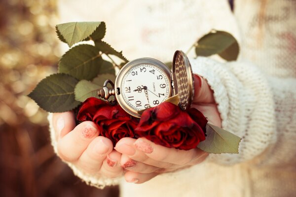 En las manos de la niña de la esfera del reloj rodeado de rosas rojas