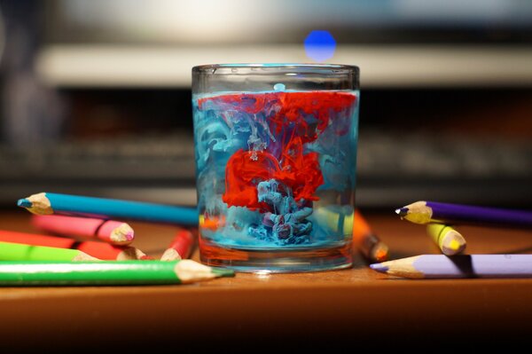 Acqua pittoresca in un bicchiere e matite colorate