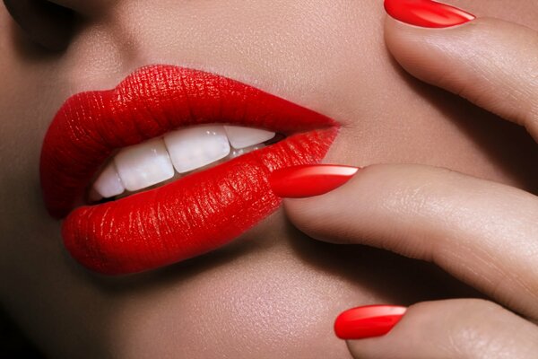 Foto macro de la cara y las manos con lápiz labial rojo y esmalte de uñas